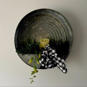 Rustic metal oil pan wall decor with candle.